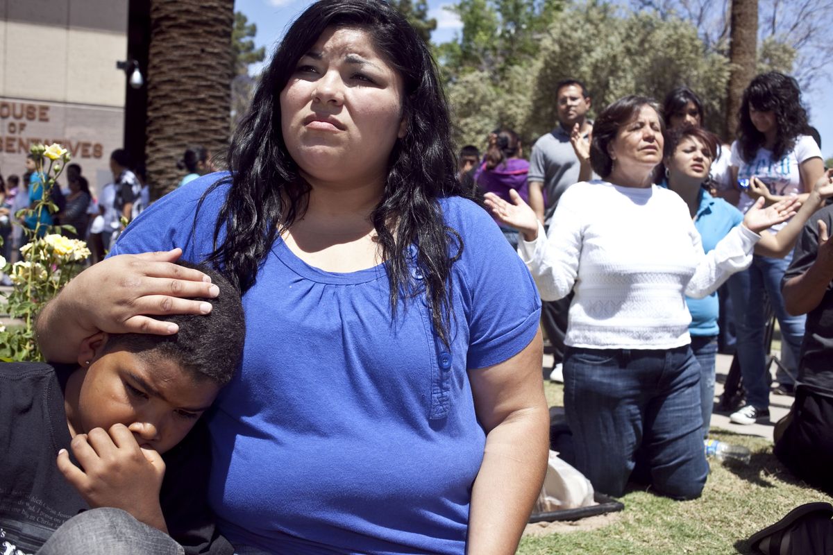 Elicia Ruiz and her son, Javier Real, 9, pray outside the Capitol in Phoenix on Friday.  (Associated Press)