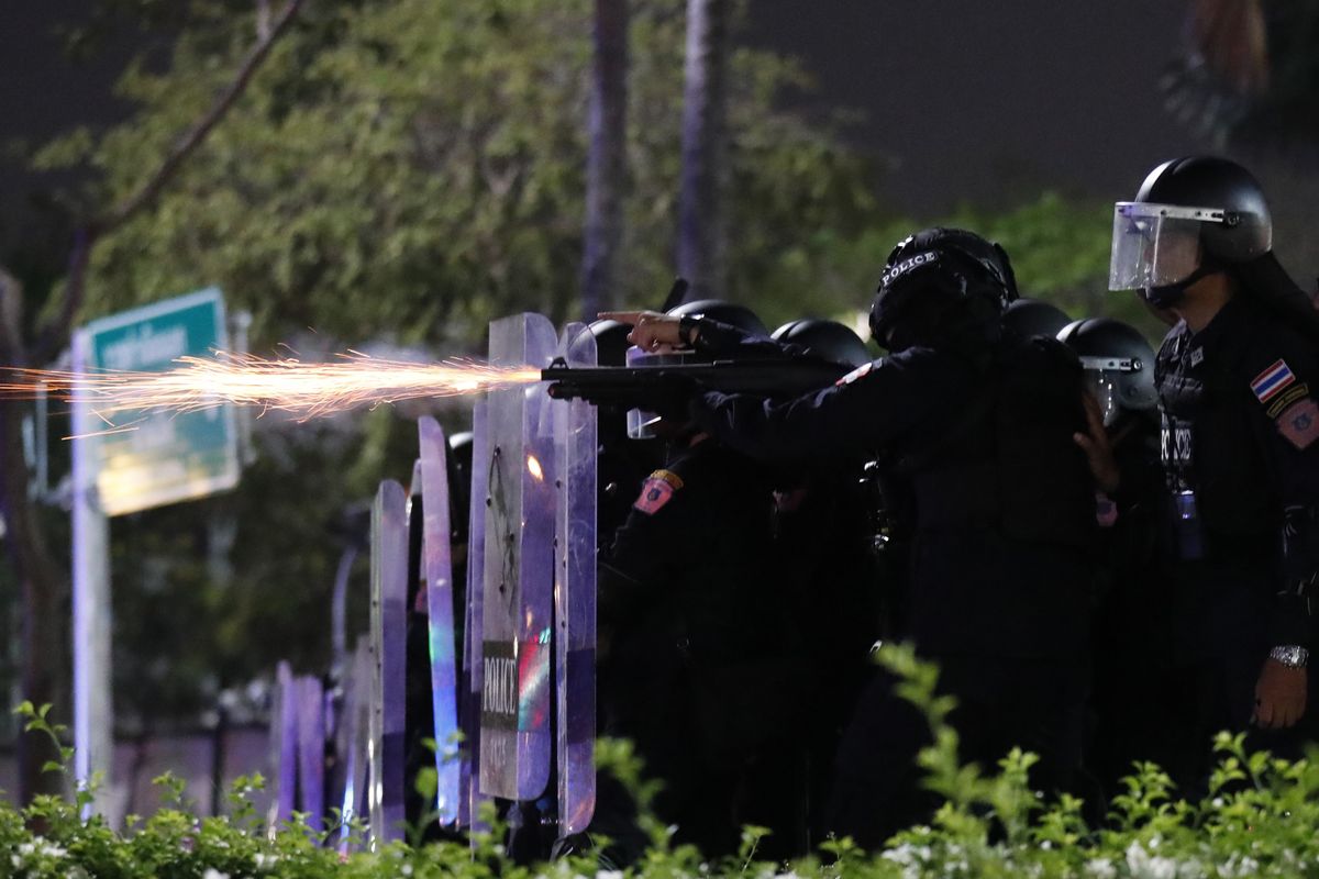 Sparks fly from the barrel of a gun used by riot police to disperse protesters who removed container vans used as a barricade in front of the Grand Palace Saturday, March 20, 2021 in Bangkok, Thailand. Thailand