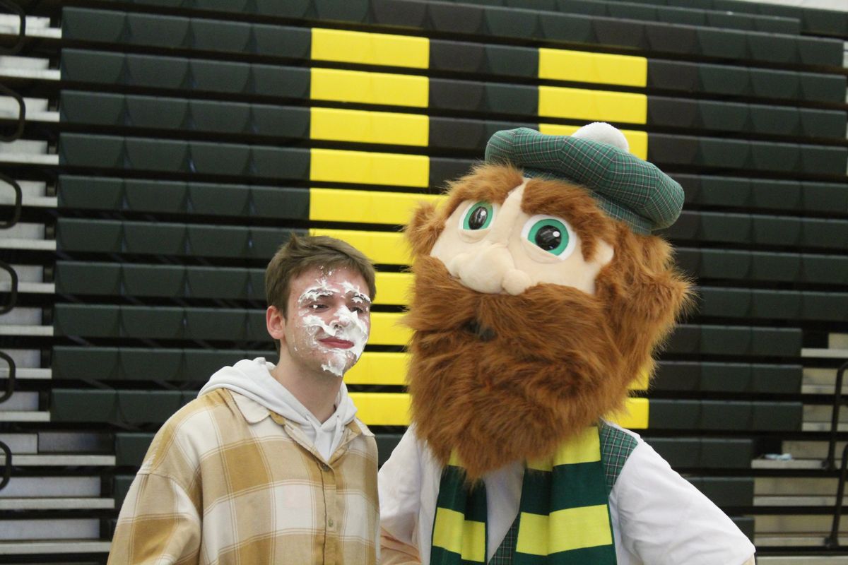 Shadle Park High School student Andrew Wilson and the school’s mascot MacTavish after Wilson lost a game of trivia against teacher Scott Harmon, resulting in a pie to the face, during the Staff vs Student Basketball Game the night of Monday December 6, 2021. Jordan Tolley-Turner/The Spokesman-Review.  (Jordan Tolley-Turner/The Spokesman-Review)