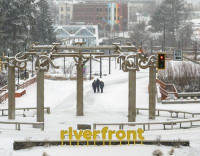 Strollers are framed by the Rotary Fountain as they make their way through Riverfront Park on Monday afternoon after about 3 inches of snow fell in the area overnight, causing traffic and travel problems in the region. More snow is possible through the weekend.  (Jesse Tinsley/The Spokesman-Review)