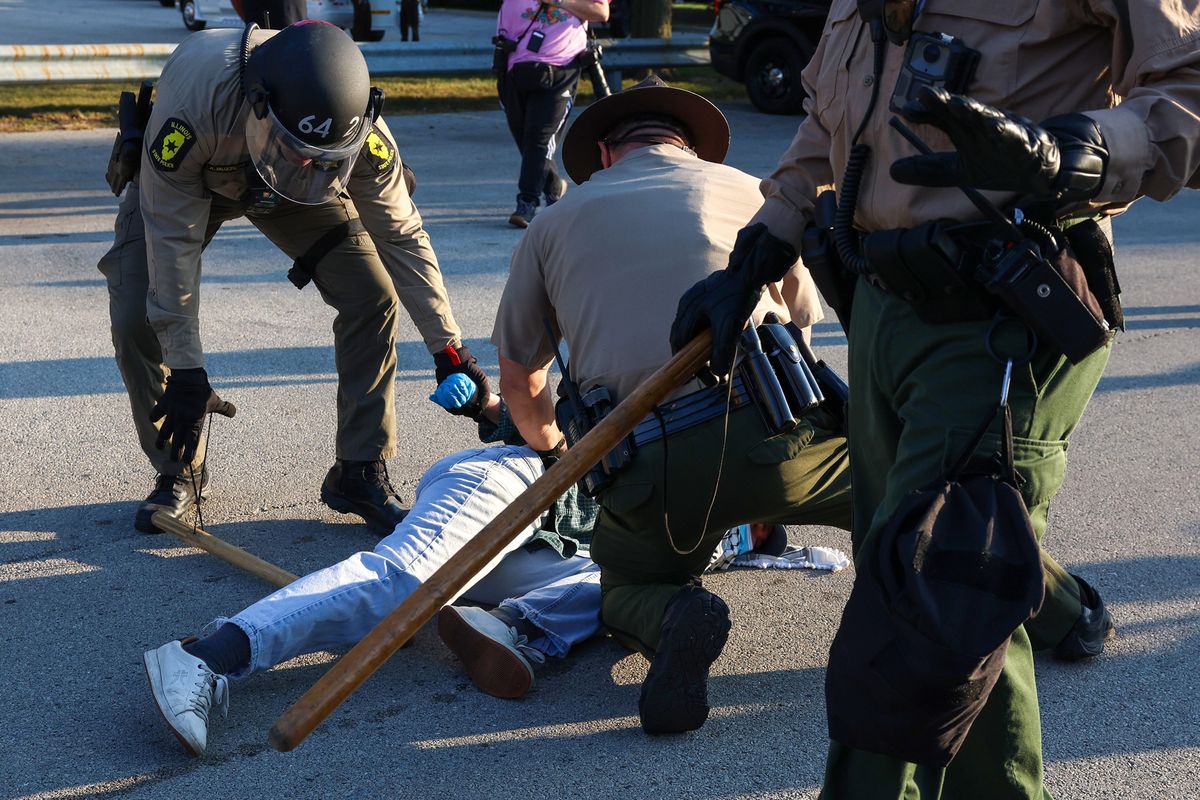 Illinois State Police troopers detain a protester who refused to back up as a vehicle passed along Harvard Street near the U.S. Immigration and Customs Enforcement holding facility in Broadview, Illinois, on Oct. 3, 2025. (Stacey Wescott/Chicago Tribune/TNS)
