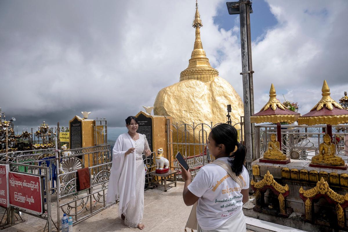 People pose for photos at the Kyite Htee Yoe Pagoda, also known as the Golden Rock Pagoda on May 28 in Mon State, an administrative division of Myanmar.  (Tribune News Service )