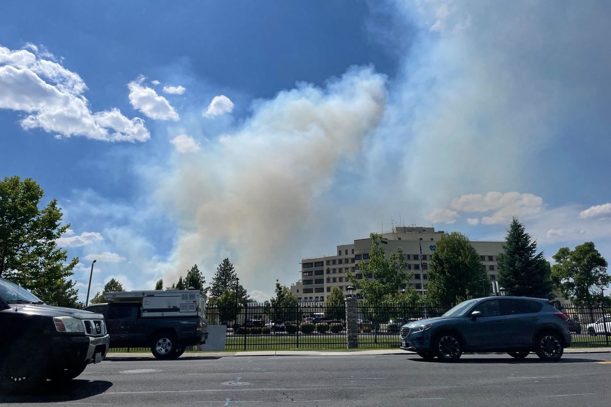 Smoke billows Sunday behind the Mann-Grandstaff Veterans Affair Medical Center on North Assembly Street in Spokane. Dozens of people were parked along Northwest Boulevard and Assembly Street watching. ( Lindsey Treffry/The Spokesman-Review)