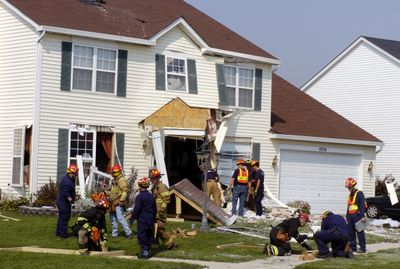 Rescue workers build support beams to stabilize a house that was struck by a helicopter in Kenosha, Wis., on Sunday. Two people in the aircraft were killed, police reported.  (Associated Press / The Spokesman-Review)