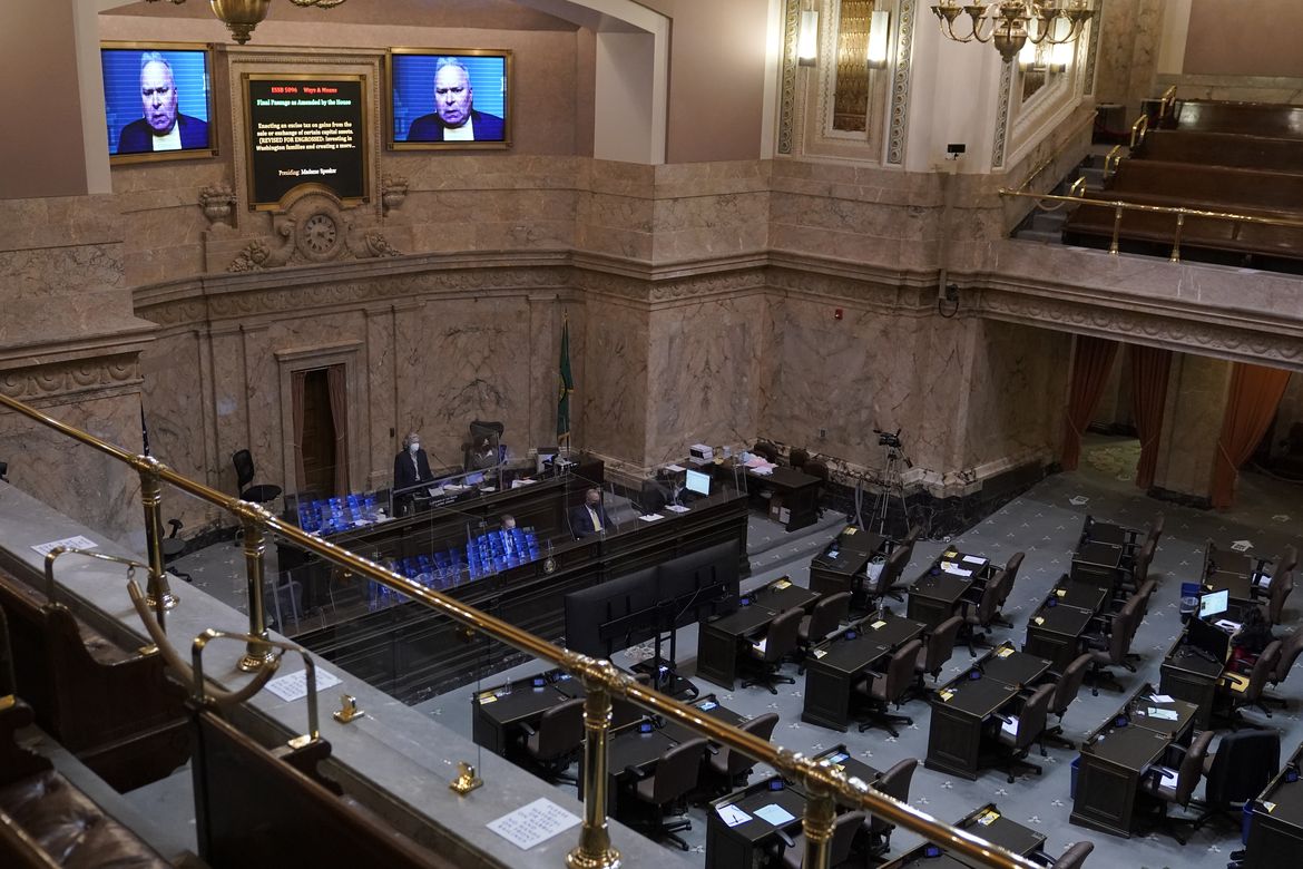 The floor of the Washington State House of Representatives chamber, with brown marble walls and rows of brown wooden desks facing the rostrum. 