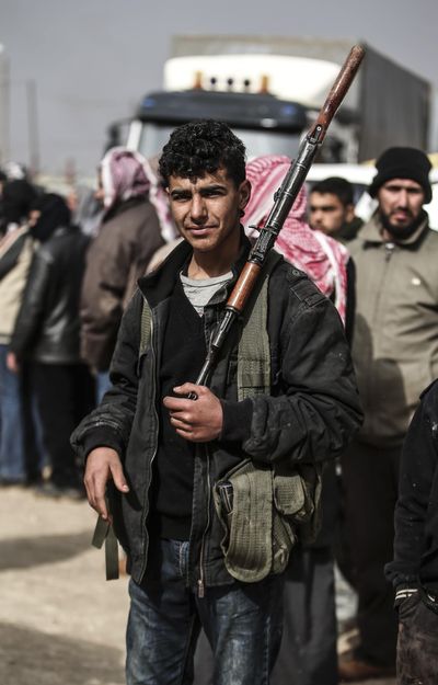 A Syrian opposition fighter  who identified himself as Belattin Katumi, holds his gun Saturday near the Bab al-Salam border. (Bunyamin Aygun / Associated Press)