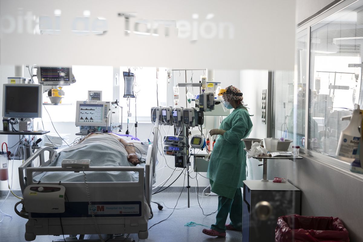 FILE - In this Oct. 6, 2020, file photo, a healthcare worker looks at a patient with COVID-19 at one of the intensive care units (ICU) at the University Hospital of Torrejon in Torrejon de Ardoz, Spain. Europe’s second wave of coronavirus infections has struck well before flu season even started. Intensive care wards are filling up again and bars are shutting down.  (Manu Fernandez)