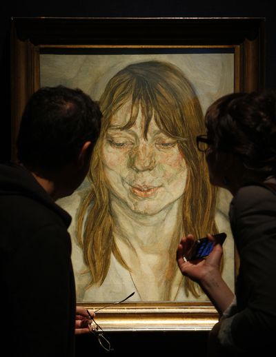 Visitors examine Lucian Freud’s “Woman Smiling” at Christie’s auction house in London on June 24. (Associated Press)