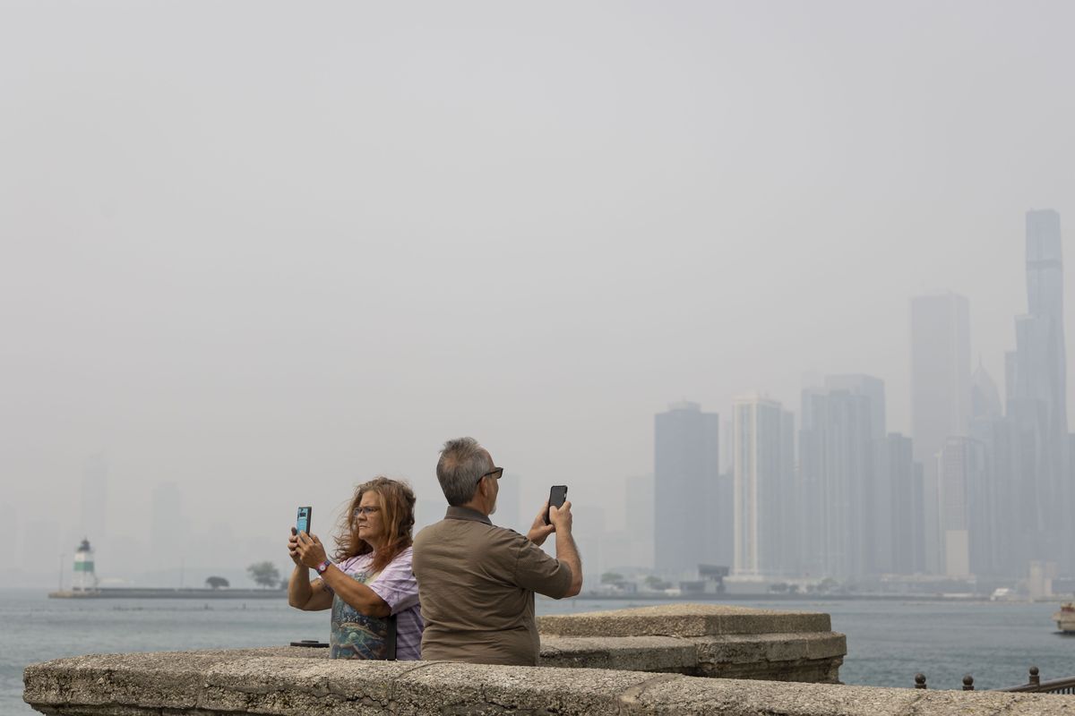 Visitors to Navy Pier photograph haze obscuring the Chicago skyline on June 27, 2023.    (Brian Cassella/Chicago Tribune/TNS)