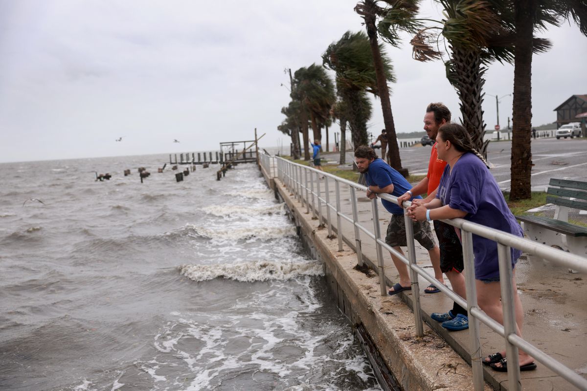 Shon Whitwood, center, and Leah Whitwood, right, stand in the wind and rain before the possible arrival of Tropical Storm Debby, which was strengthening as it moved through the Gulf of Mexico on Sunday in Cedar Key, Fla.  (Joe Raedle)