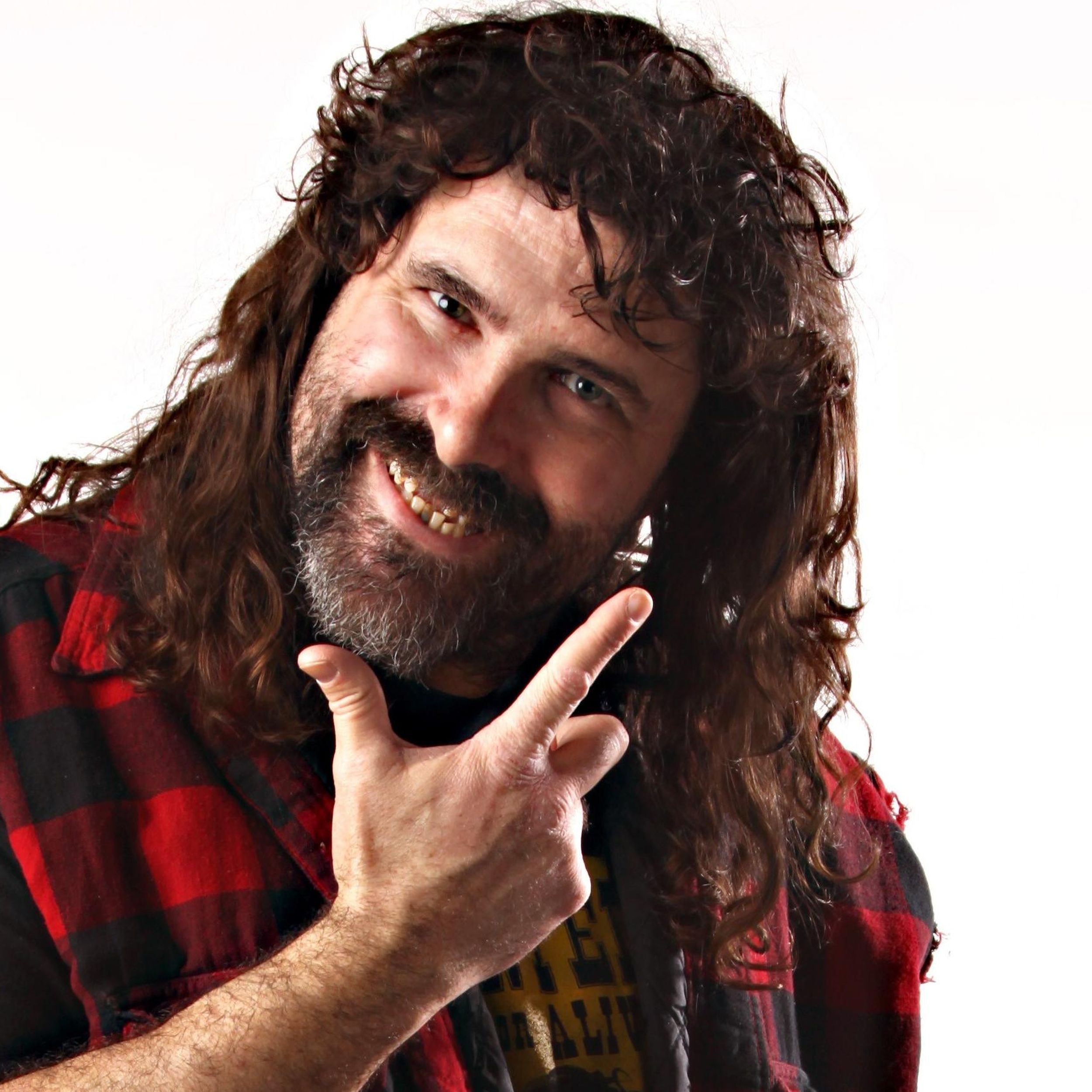 Mick Foley, head titled, grinning for the camera, hand in 