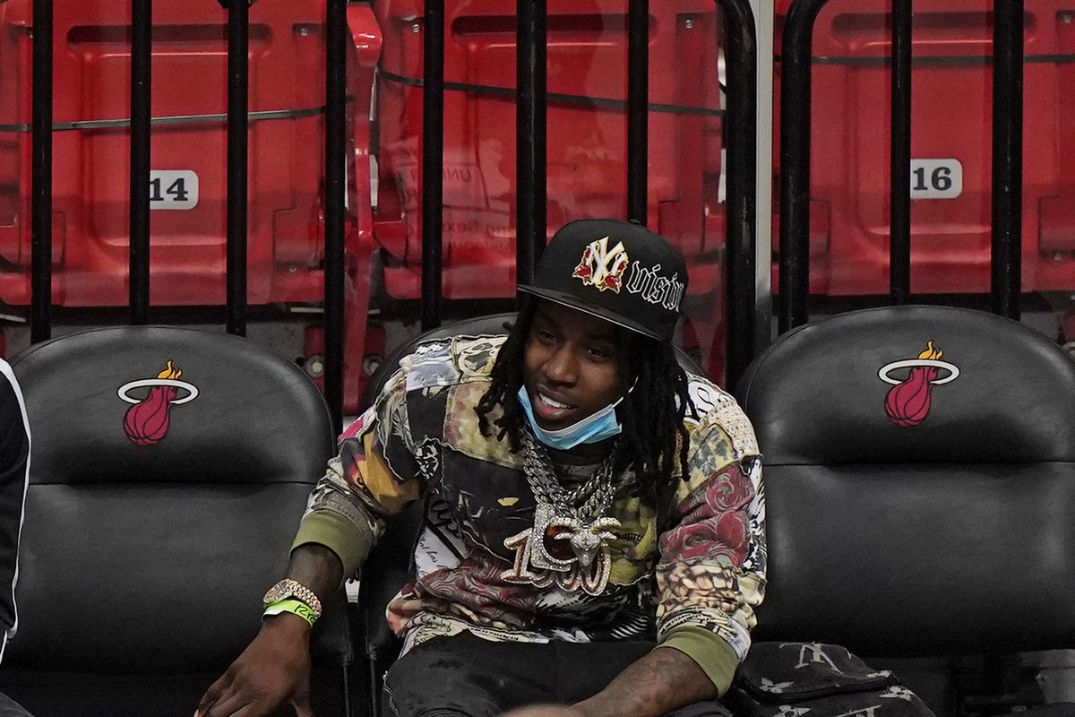 In this April 18, 2021 photo, Rapper Polo G watches during the second half of an NBA basketball game between the Miami Heat and the Brooklyn Nets in Miami. Officials say rapper Polo G has been arrested in Miami on charges including battery on a police officer, resisting arrest with violence and criminal mischief. Jail records show 22-year-old Taurus Bartlett was booked into jail on Saturday, June 12, 2021.  (Wilfredo Lee)