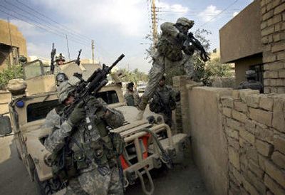 
American soldiers from the 10th Mountain Division climb over a brick wall to search an  Iraqi home during a patrol in western Baghdad on Monday. 
 (AFP/Getty Images / The Spokesman-Review)