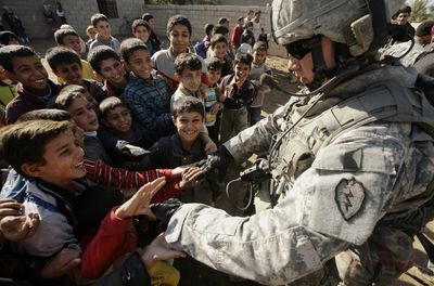 U.S. Army Staff Sgt. Dustin Gillette, 25, from Sioux Falls, S.D., greets Iraqi schoolchildren during a patrol in the village of Abu Seeyah in Diyala province north of Baghdad Wednesday. (Associated Press / The Spokesman-Review)