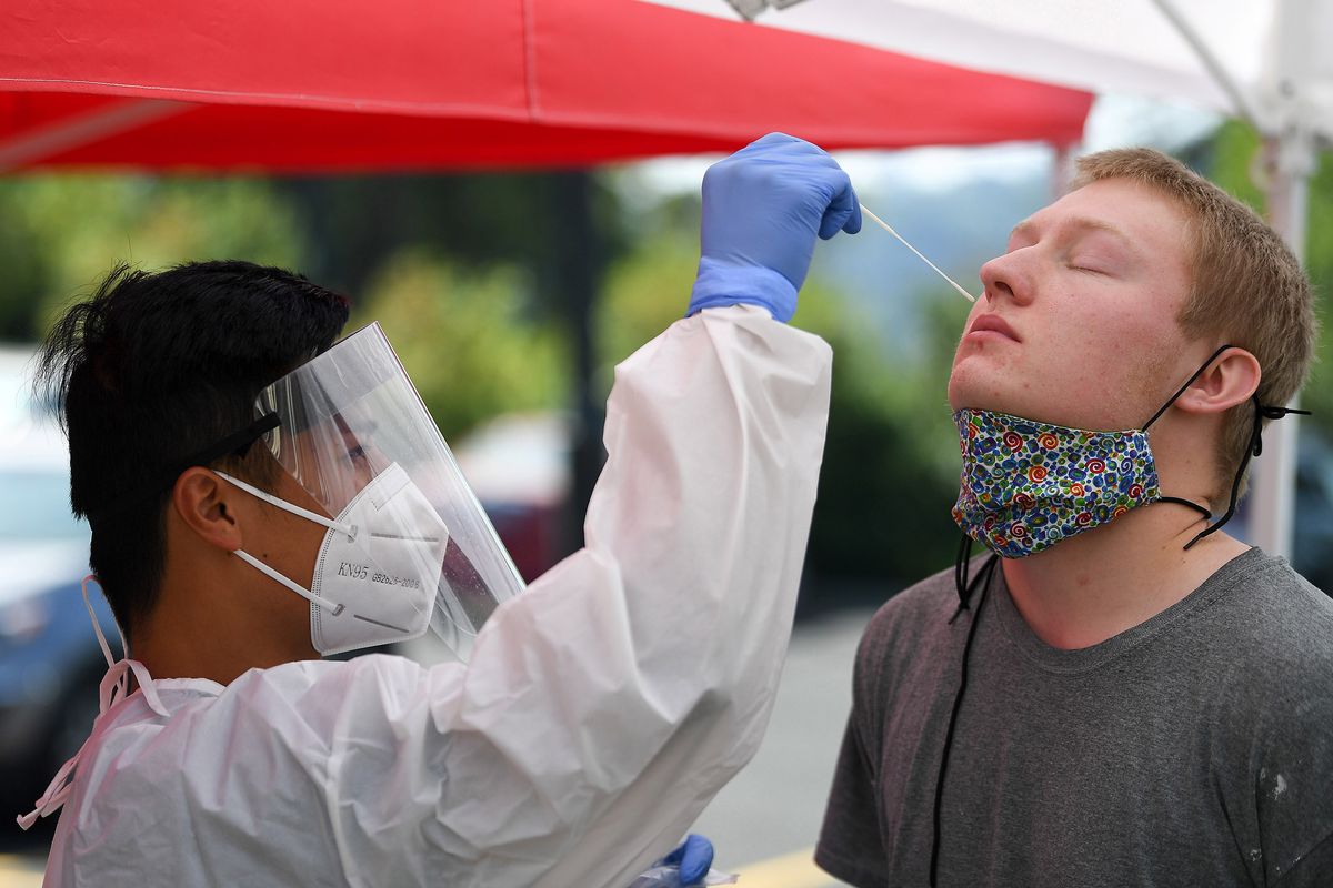 Huy Bui, left, a second-year pharmacy student at WSU, administers a COVID-19 test to Conrad Soran, a fourth-year mechanical engineering major at a mobile testing site on WSU’s campus on Wednesday.  (Tyler Tjomsland/THE SPOKESMAN-REVIEW)
