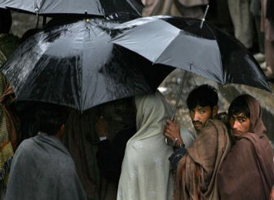 
Pakistanis wait in the rain to receive food  in the town of Bagh, in Pakistani Kashmir on Sunday. Pakistan is concentrated on helping the millions left homeless and the tens of thousands that were injured by an Oct. 8th earthquake before winter. 
 (Associated Press / The Spokesman-Review)