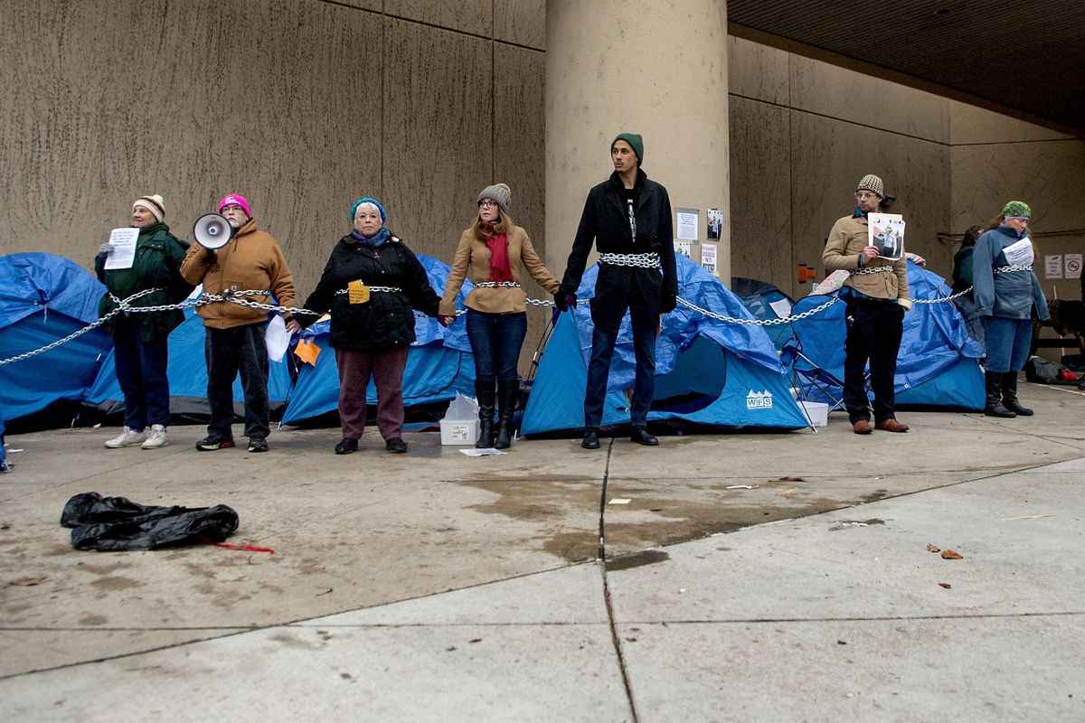 Members of the community including city council member Kate Burke, center and Devon Wilson, center right, were chained together to protest the removal of Camp Hope, a tent city for the homeless in front of City Hall in Spokane on Saturday, Dec. 8, 2018 (Kathy Plonka / The Spokesman-Review)