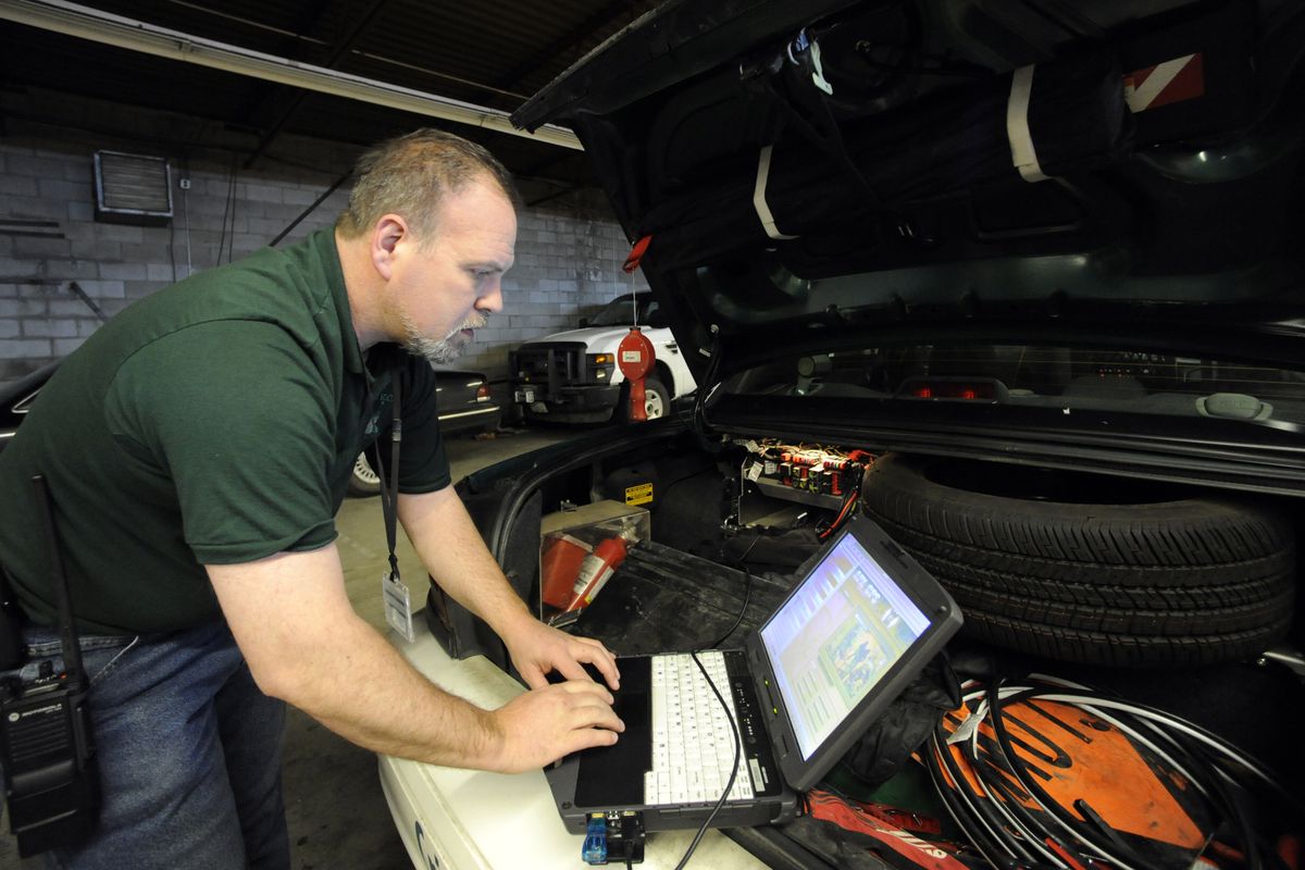 Communication technician Ric Hunt attaches a computer to the new radio unit in the trunk of a Spokane County sheriff’s patrol car and checks its functions Tuesday in a Spokane County maintenance garage. (Jesse Tinsley)