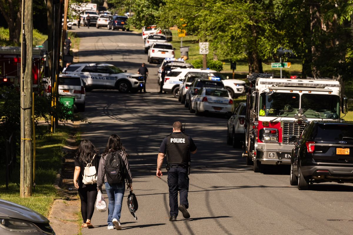 A Charlotte Mecklenburg Police Department officer, right, escorts two young girls trying to get home after school near the scene of a shootout on the 5000 block of Galway Drive in east Charlotte, N.C., on Monday.  (Melissa Melvin-Rodriguez/Charlotte Observer)