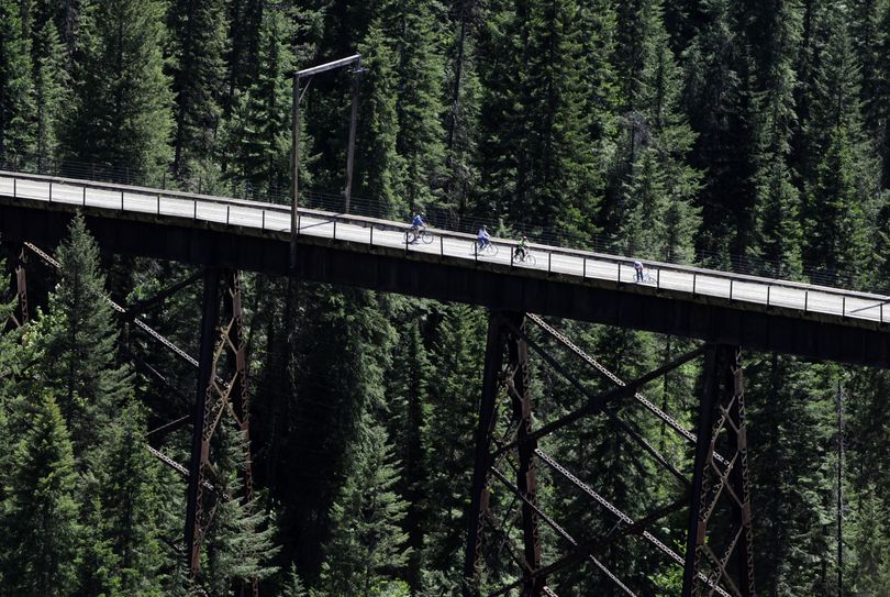 Bicyclists, dwarfed by one of several trestles and the surrounding beauty of the national forest, stop to admire the view in 2008 along the Route of the Hiawatha, a trail that follows the path of the long-gone railroad through the region on the Montana-Idaho border.   (File)