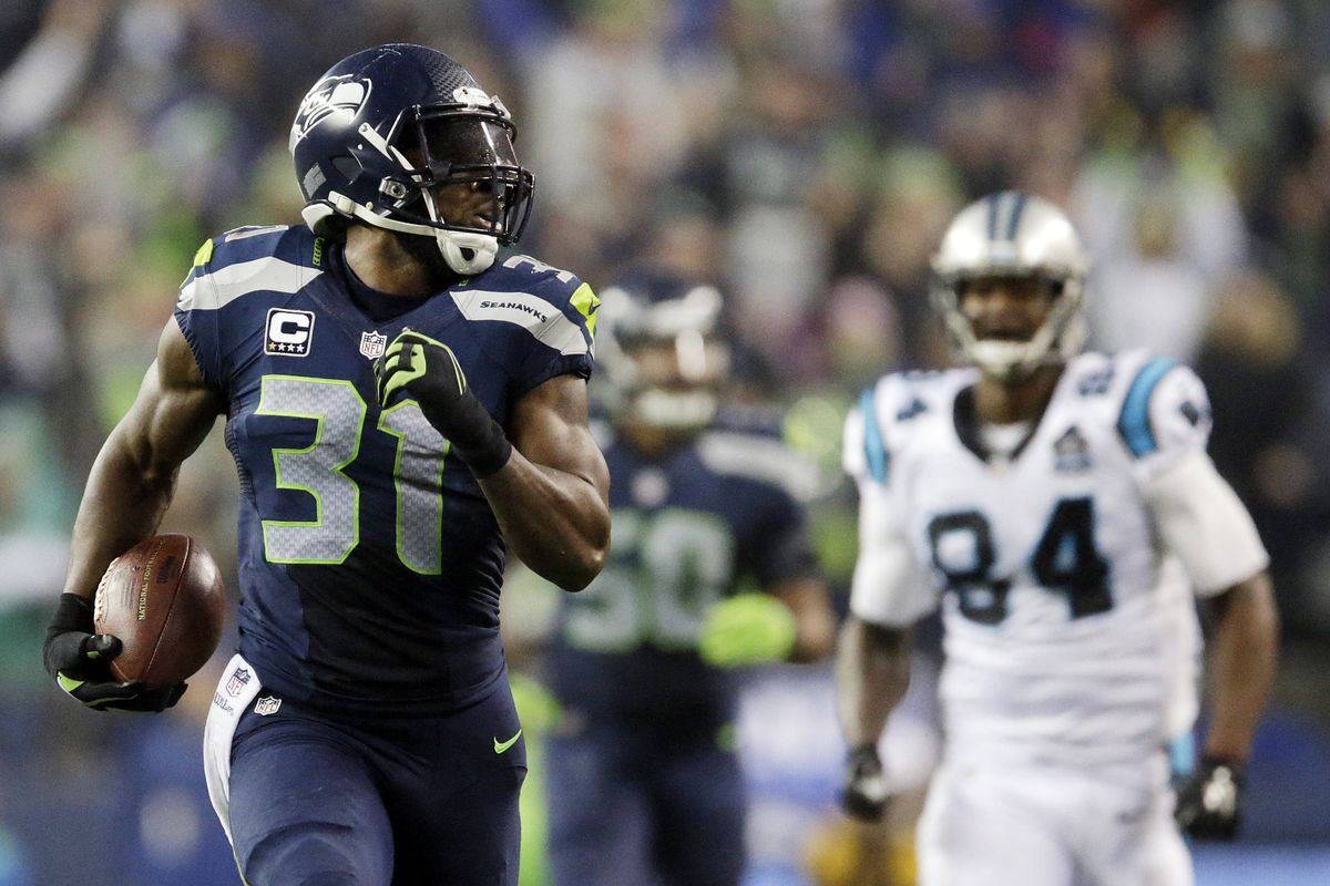 Seahawks safety Kam Chancellor leaves Carolina’s Ed Dickson in rear-view mirror on his way to interception-return touchdown. (Associated Press)