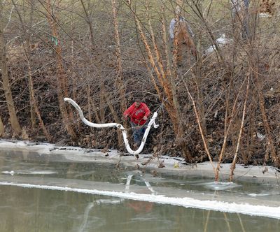 A worker places a boom in the Elk River on Thursday where a chemical leak in Charleston, W.Va., has fouled drinking water. (Associated Press)