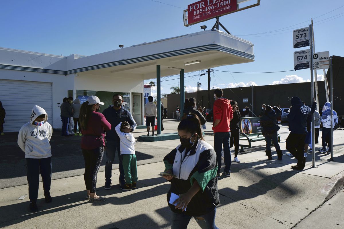 People line up for a free COVID-19 rapid test at a gas station in the Reseda section of Los Angeles on Sunday, Dec. 26, 2021, as California braces for a post-holiday virus surge.  (Richard Vogel)