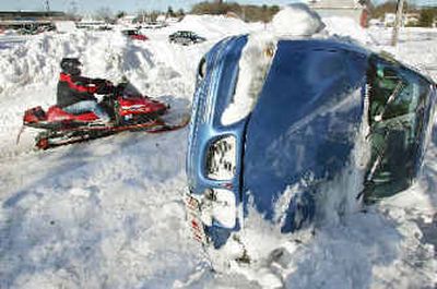 
A snowmobiler drives past an upturned car on a snowbank in Hyannis, Mass., on Monday. A man who said he is the car's owner claimed a snowplow had pushed the unattended vehicle onto the mound of snow during a blizzard Sunday. 
 (Associated Press / The Spokesman-Review)
