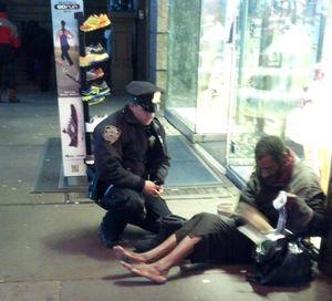 This photo provided by Jennifer Foster shows New York City Police Officer Larry DePrimo presenting a barefoot homeless man in New York's Time Square with boots Nov. 14, 2012 . Foster was visiting New York with her boyfriend on Nov. 14, when she came across the shoeless man asking for change in Times Square. As she was about to approach him, she said the officer  came up to the man with a pair of all-weather boots and thermal socks on the frigid night. She took the picture on her cellphone. It was posted Tuesday night to the NYPD's official Facebook page and became an instant hit. More than 350,000 users "liked" it as of Thursday afternoon, and over 100,000 shared it. (Jennifer Foster / Jennifer Foster )