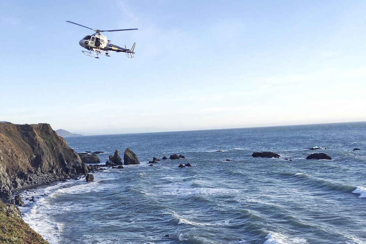 This photo provided by the California Highway Patrol shows a helicopter hovering over steep coastal cliffs Tuesday, March 27, 2018, near Mendocino, Calif., where a vehicle, visible at lower right, plunged about 100 feet off a cliff along Highway 1. The California Highway Patrol identified the victims Tuesday as two women from West Linn, Ore., and six children. (Associated Press / California Highway Patrol)
