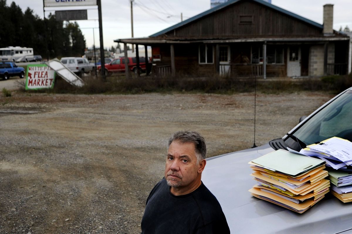 Developer Alan Johnson stands with stacks of documents from a lawsuit against him at the intersection of highways 95 and 54 in Athol. A fight with the Idaho Transportation Department has held up development of a travel center, grocery store and hotel on the site. (Kathy Plonka)