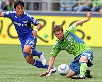 Seattle’s Pat Noonan, right, goes to the turf to protect the ball from Kansas City’s Roger Espinoza. (Associated Press)