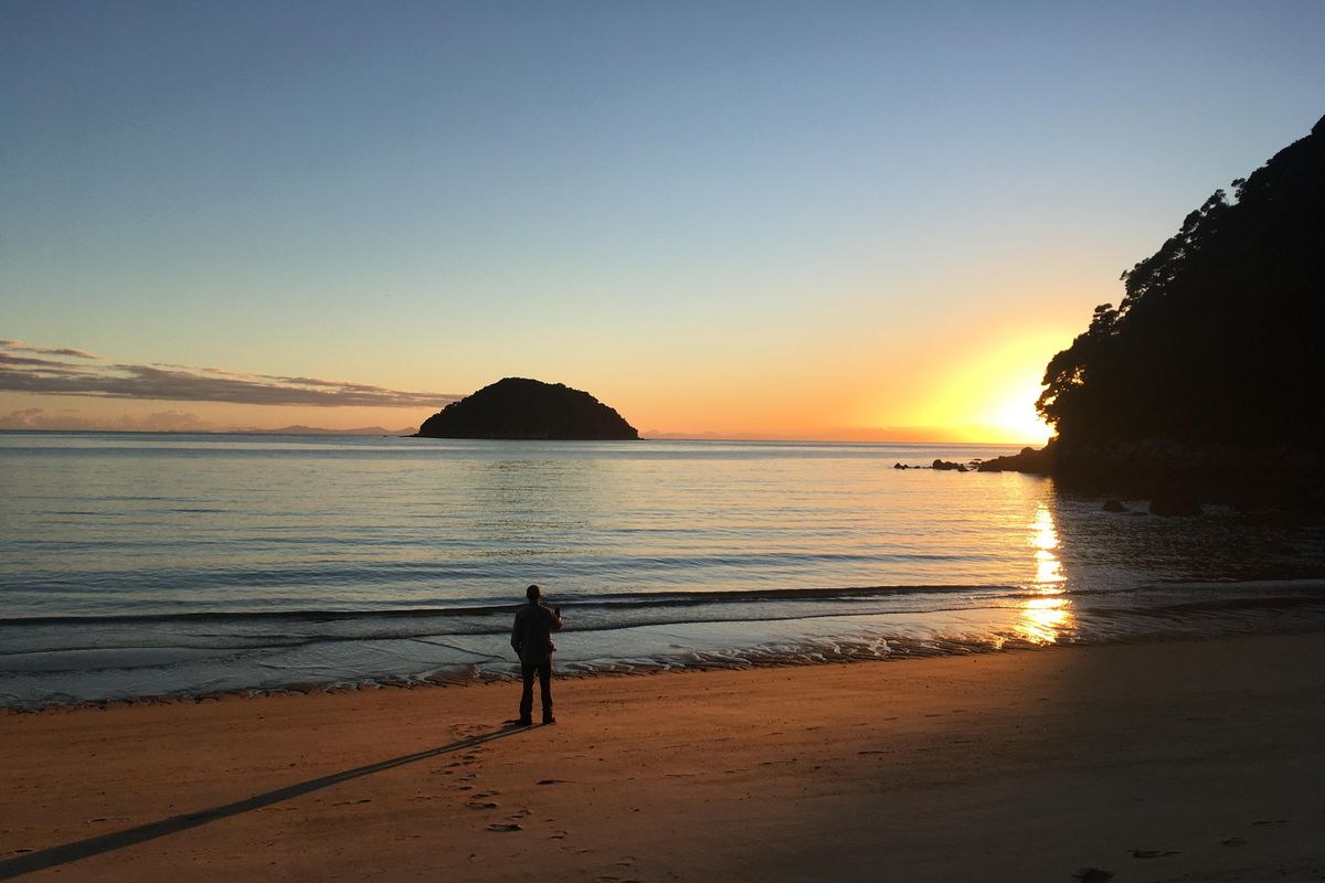 Alone with his thoughts, a satisfied hiker surveys a golden sunset on the Abel Tasman Coast Track in New Zealand. (William Brock / Courtesy)