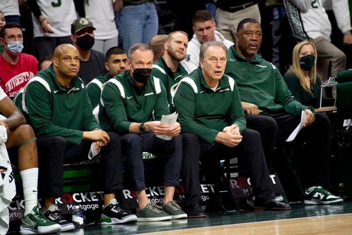 Michigan State assistant coach Doug Wojcik, wearing a mask and seated next to head coach Tom Izzo (pictured right), watches the action during a home game against Wisconsin last season.  (Tribune News Service)