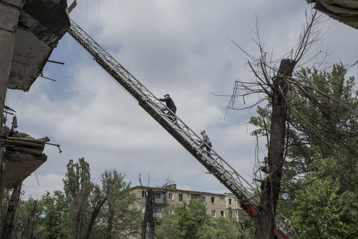 A firefighter, left, and a resident climb a fire truck