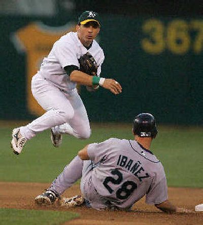 
Oakland's Marco Scutaro hops over Seattle's Raul Ibanez to turn a double play.
 (Associated Press / The Spokesman-Review)