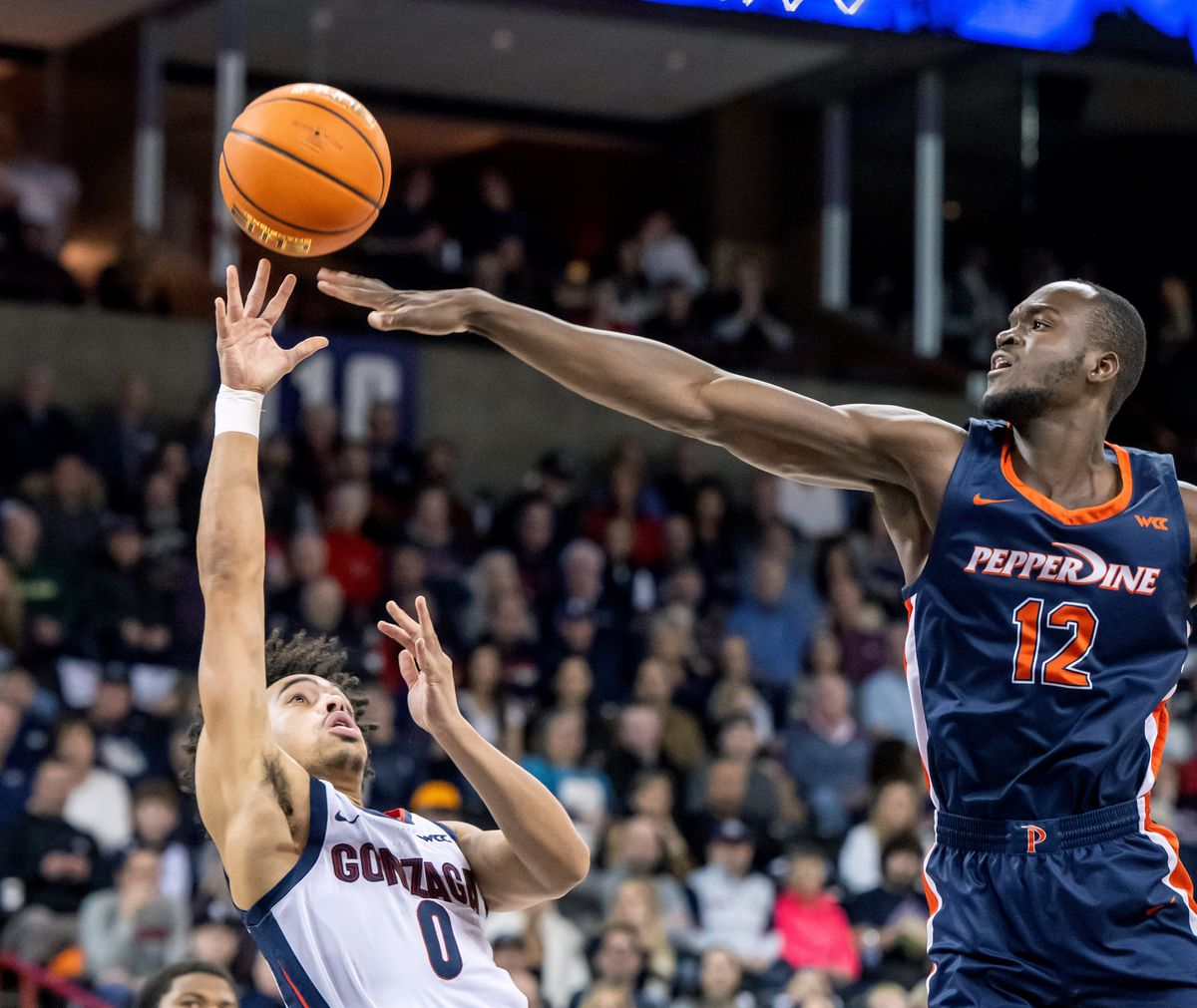 Gonzaga guard Ryan Nembhard (0) takes a shot over the fingertips of Pepperdine forward Boubacar Coulibaly (12) during the first half of a NCAA college basketball game, Thursday, Jan. 4, 2024, in the Spokane Veterans Arena.  (COLIN MULVANY)