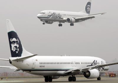 An Alaska Airlines plane comes in for a landing as another taxis for takeoff at Seattle-Tacoma International Airport in Seattle. Alaska Air Group Inc., operator of Alaska Airlines and Horizon Air, reported a fourth-quarter loss of $75.2 million in January. (File Associated Press / The Spokesman-Review)