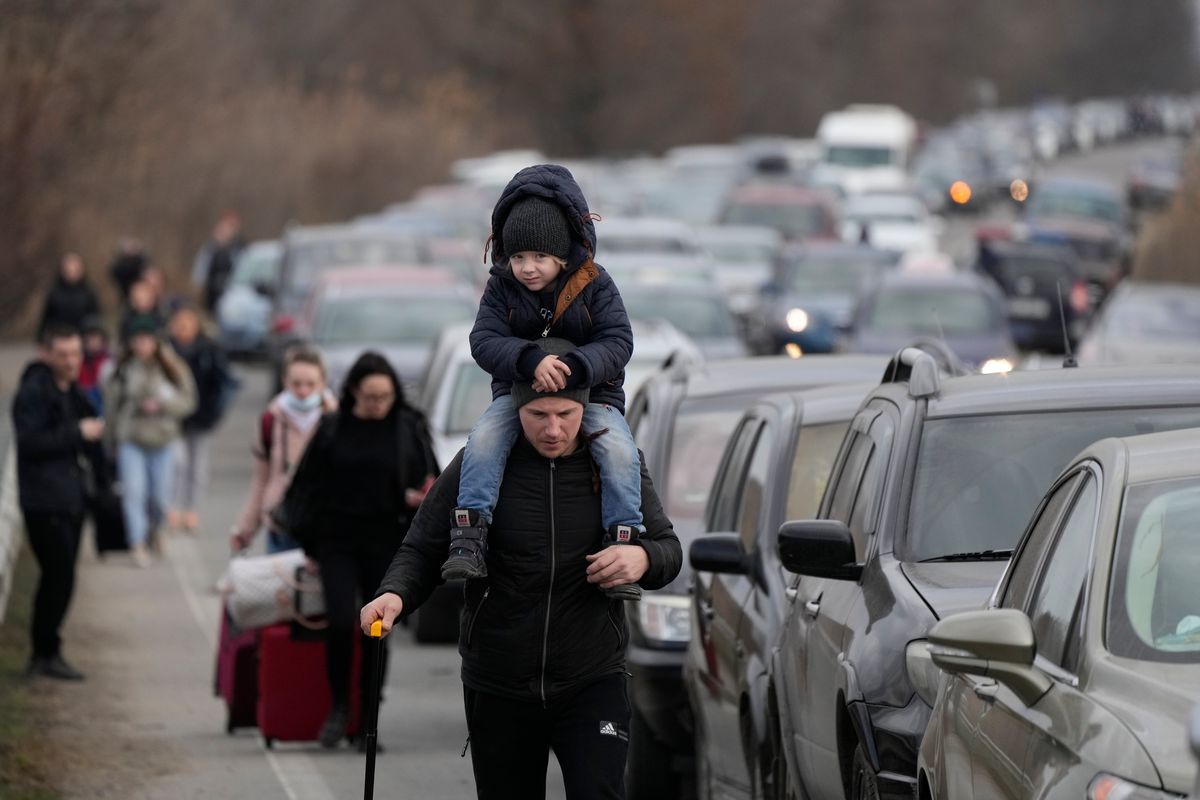 Ukrainian refugees walk along vehicles lining up to cross the border from Ukraine into Moldova, at Mayaky-Udobne crossing border point Saturday near Mayaky-Udobne, Ukraine.  (Sergei Grits)