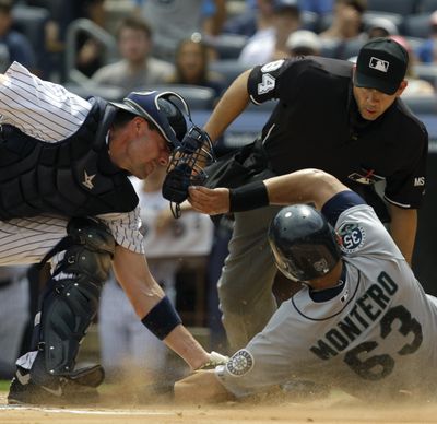 Umpire Angel Campos, right, watches as Yankees catcher Chris Stewart tags out Mariners’ Jesus Montero. (Associated Press)