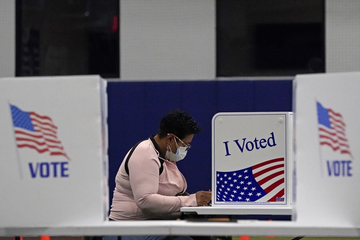 FILE - In this Nov. 3, 2020, file photo, a woman votes at the MLB Urban Youth Academy in Kansas City, Mo. U.S. voters went to the polls starkly divided on how they see President Donald Trump’s response to the coronavirus pandemic, with a surprising twist. In places where the virus is most rampant now, Trump enjoyed enormous support.  (Charlie Riedel)