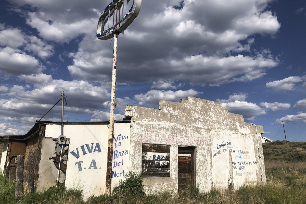 In this June 28, 2020, photo, an abandoned gas station in Tierra Amarilla, N.M., is shown with graffiti honoring the 1967 courthouse raid in the town by armed Mexican American land grant activists. Activists and cities are left wondering what to do with empty spaces that once honored historic figures tied to racism as statues and monuments fall. New Mexico has no formal public art honoring the Tierra Amarilla raid, which helped spark the Chicano Movement.  (Russell Contreras)