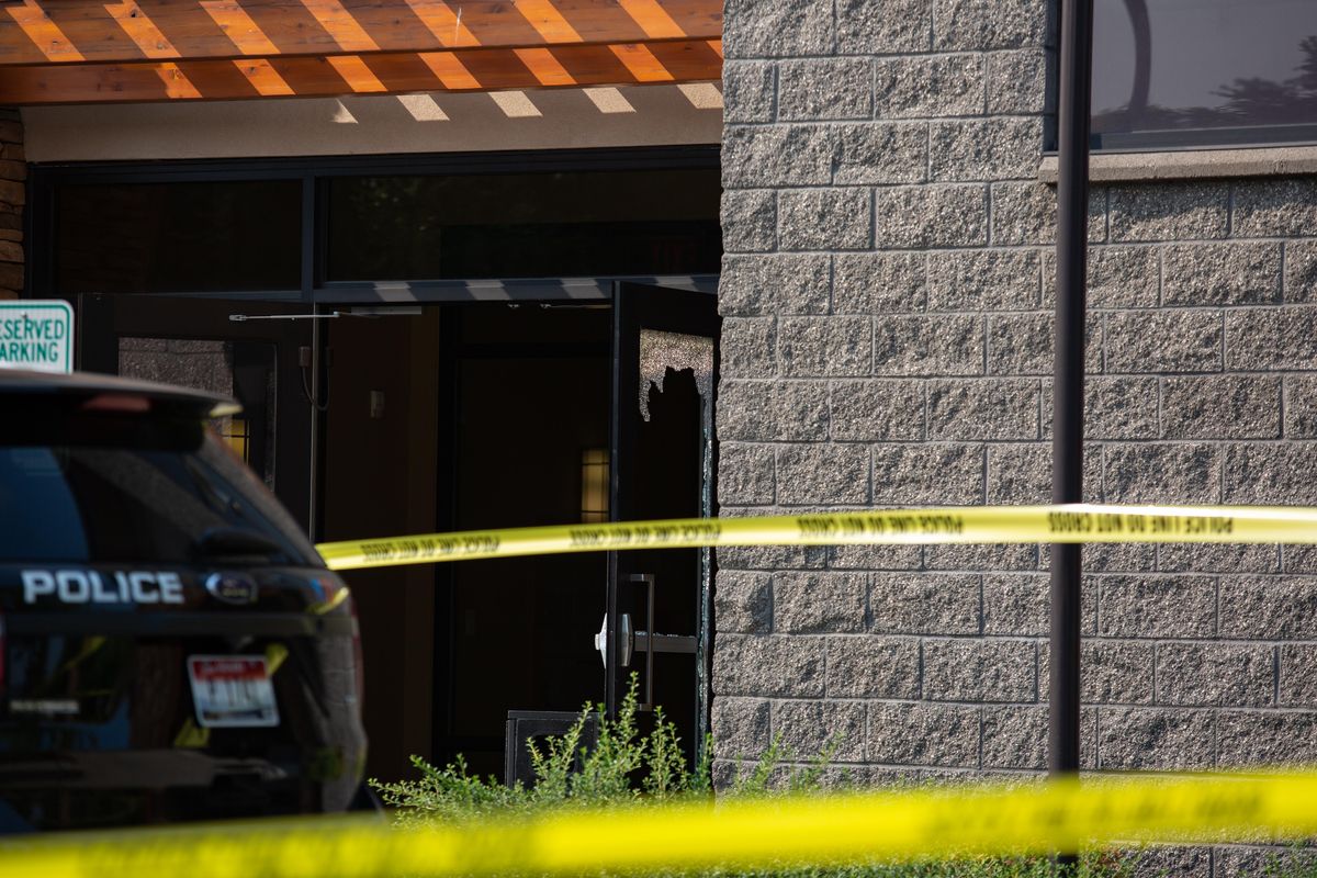 Broken glass is seen along with a Coeur d’Alene police vehicle at the Global Credit Union Coeur d’Alene branch, where a suspect died on the afternoon of Saturday, Aug. 11, 2018 from a gunshot wound received from an armed security guard. (Libby Kamrowski / The Spokesman-Review)