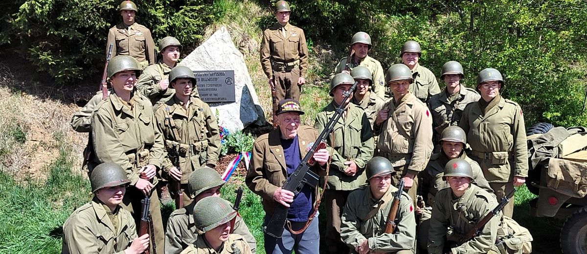 Harry Humason, center, stands in front of a memorial for his Army division that helped liberate Czechoslovakia in World War II. 