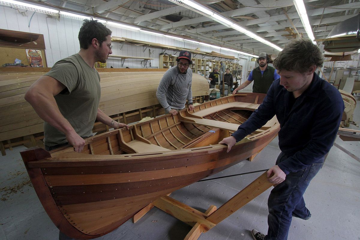 Students Zach Simonson-Bond, from left, Dan Bamberger, Griffin Myers and Paul Lyter prepare to flip a cedar-planked skiff at the Northwest School of Wooden Boatbuilding.