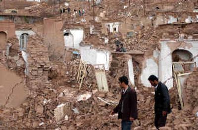 
People walk past earthquake damaged houses Tuesday in Dahoueieh village on the outskirts of Zarand, Iran. 
 (Associated Press / The Spokesman-Review)