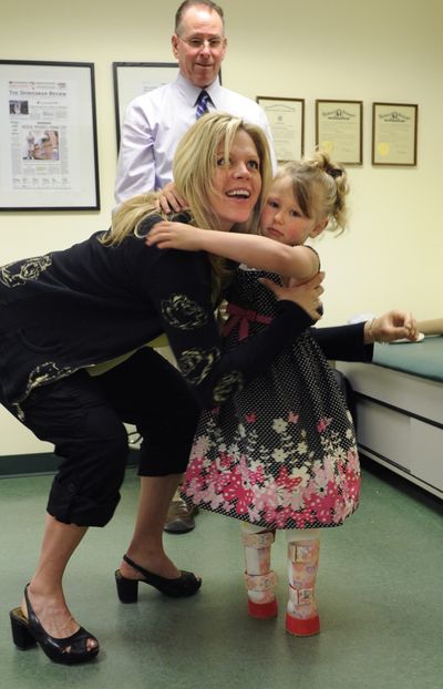 Hanger Prosthetics and Orthotics patient advocate Carrie Davis picks up Kyra Wine, 5, after she tried out her new prosthetic “stubbies” that will allow her to play outside.  Practitioner Don Christenson, who fitted Kyra, is in the background. (Colin Mulvany)