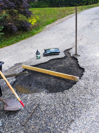 This large area of my asphalt driveway crumbled. I’ve removed all the bad pavement and removed dust from the edges, and I have all the tools ready. It’s time to install the patch.  (Tribune Content Agency)