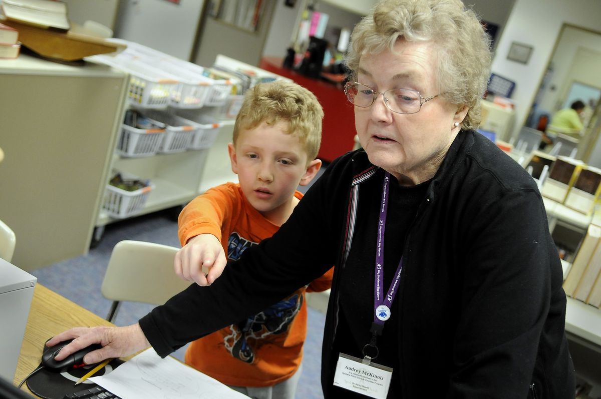 Willard Elementary School volunteer Audrey McKinnis helps third-grader  Aiden Hamby search for information about Louis Davenport on Wednesday in the school’s library. He was working on a report.  (Dan Pelle / The Spokesman-Review)