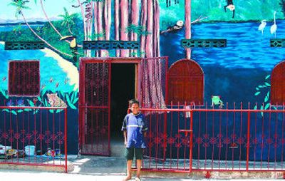 
A young student stands in front of Spokane artist Katherine Staib Derrick's finished tropical mural on a school for empoverished children in Granada, Nicaragua. 
 (The Spokesman-Review)